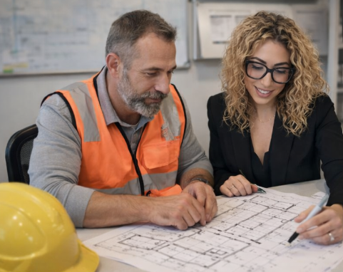 Interior designer reviewing floorplans with builder on residential construction site
